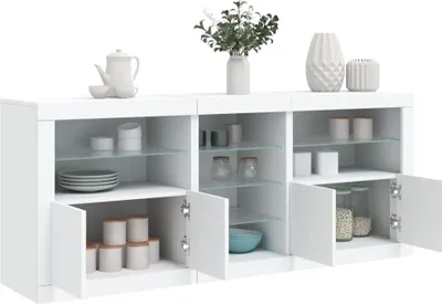 A white sideboard with open doors displaying items inside and decorative elements on top.