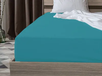 A close-up view of a turquoise fitted sheet on a bed.
