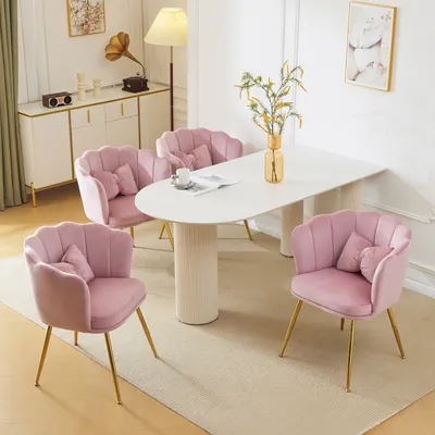 A dining set with four pink velvet chairs and a white oval table in a well-lit room.