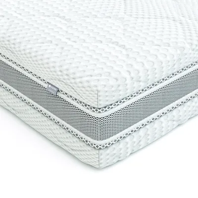 A close-up, angled view of a white mattress with a textured surface and a gray mesh band around the side.