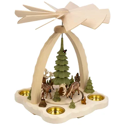 Ein hölzernes Weihnachtspyramidenkarussell zeigt eine winterliche Szene mit Rehen und Tannenbäumen umgeben von vier Teelichthaltern und einem großen Propeller oben.