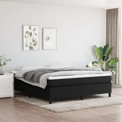 A bedroom setting featuring a black bed frame with a mattress and bedding.