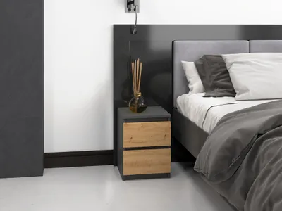A modern nightstand with two drawers next to a bed.