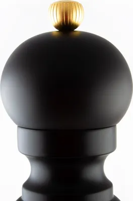 A close-up of the top part of a black pepper mill with a gold knob.