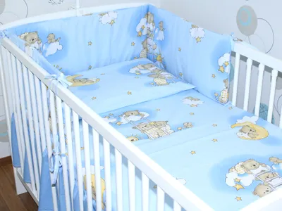 A baby crib with blue bedding featuring teddy bears and stars.