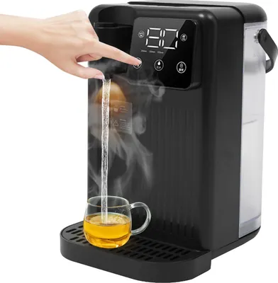 A hand is pressing a button on a black instant hot water dispenser, dispensing hot water into a clear glass mug filled with tea. Steam is rising from the water.