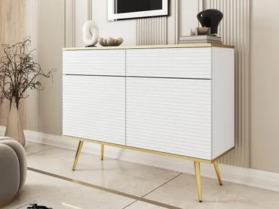 A white and gold sideboard with decorative doors and drawers, standing on gold legs, in a well-lit room.