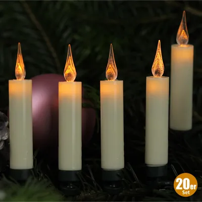 A set of LED Christmas tree candles placed among evergreen branches and a decorative ornament.