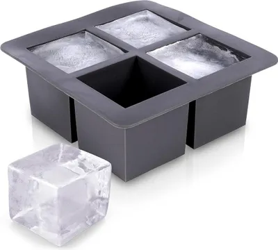 A gray silicone ice cube tray with four large square molds, two of which contain ice. A single large ice cube sits in front of the tray.