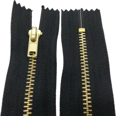 A close-up view of a black zipper with gold-colored teeth and slider.