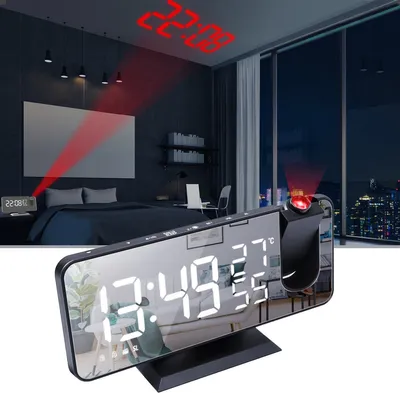 A digital alarm clock with a projection feature is shown in a bedroom setting at night, with the projected time visible on the ceiling.