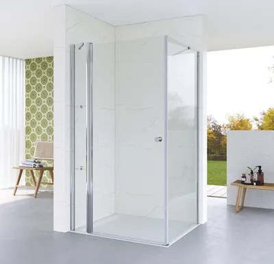A modern bathroom with a glass shower enclosure, white marble tiles, and a patterned wallpaper.