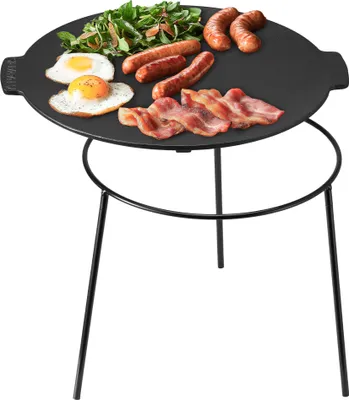 A breakfast spread on a round cast iron grill plate with a tripod stand.
