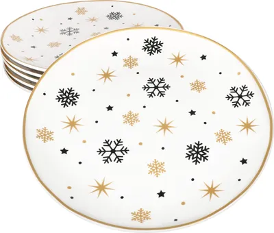 A stack of white plates with a gold rim, decorated with black and gold snowflakes and stars.