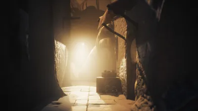 A dimly lit hallway with a bright light source at the end, illuminating a figure.