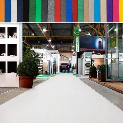 A trade show or exhibition hall with various booths and displays, featuring a white carpeted aisle.