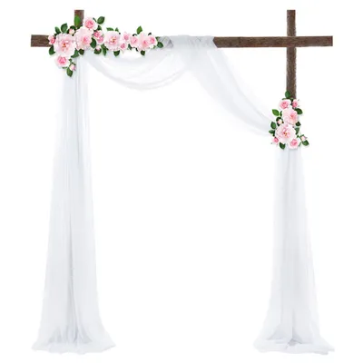 A wedding arch decorated with white fabric and pink flowers.