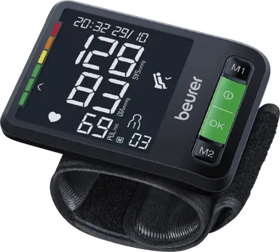 A close-up shot of a black wrist blood pressure monitor with a digital display and green buttons.