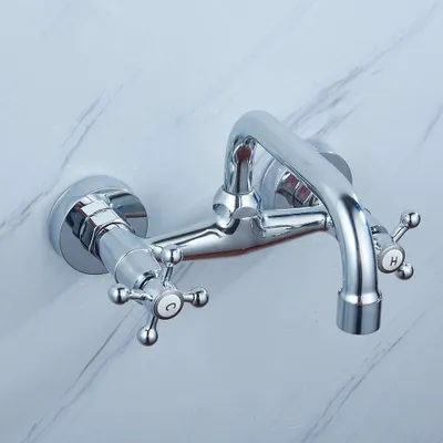 A chrome-finished wall-mounted faucet with two handles, one marked 'C' and the other 'H', against a marble-patterned wall.
