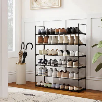 A shoe rack filled with various types of shoes and two umbrellas in a stand next to it, placed in a hallway or entry way.