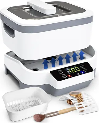 A white ultrasonic cleaner with a gray lid and control panel, shown with accessories like a basket, a watch, and a makeup brush.