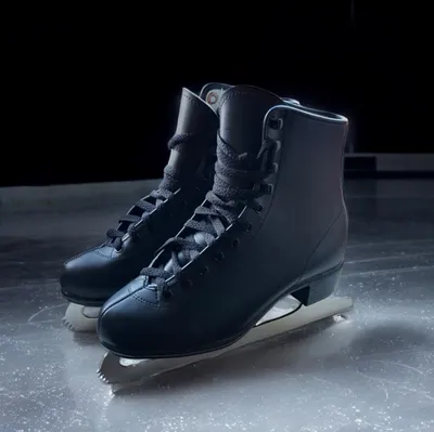 A pair of black ice skates on an ice rink.