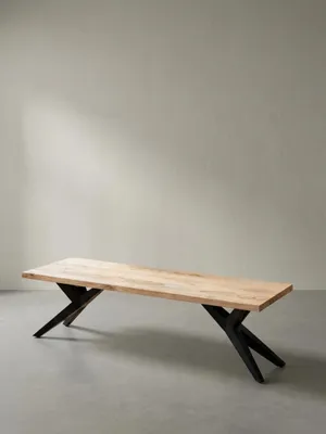Schräge Perspektive der massiven Holzbank, die die Tiefe der 4 cm dicken Sitzplatte aus Akazie und die skulpturale Form des schwarzen Metallgestells zeigt._#sku_SAFWL7.229#