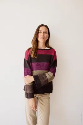 A woman wearing a striped sweater and beige pants against a white background.