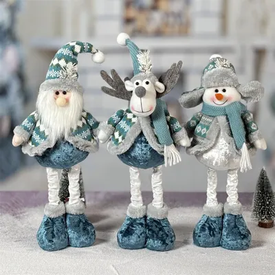 Three Christmas-themed plush figures (Santa, reindeer, snowman) standing on a surface with a blurred background.