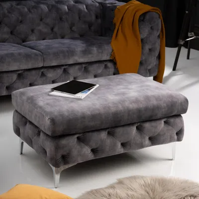 A tufted ottoman in front of a tufted sofa.