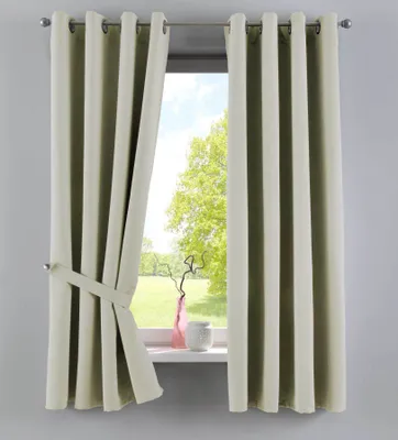 A pair of beige curtains are shown tied back with a fabric tie, revealing a window with a view of trees and a grassy field. A pink vase and a white decorative object sit on the windowsill.