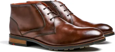 A pair of brown leather chukka boots on a white background.