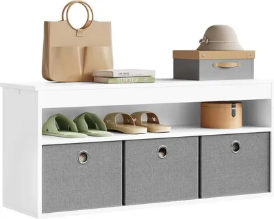 A white shoe bench with three gray fabric storage drawers, displaying various items on its top surface and inside the drawers.