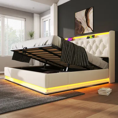 A modern bedroom with a white upholstered bed frame featuring LED lighting and a tufted headboard. The bed is shown with its storage compartment open, revealing a slatted mattress base.