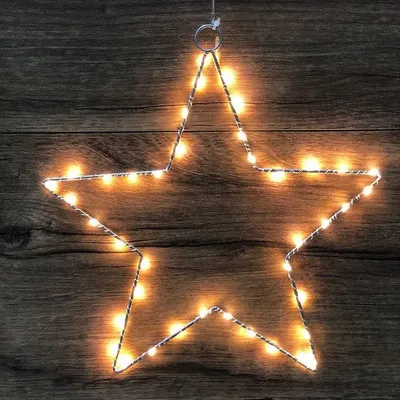 A star-shaped LED light decoration hanging against a wooden background.