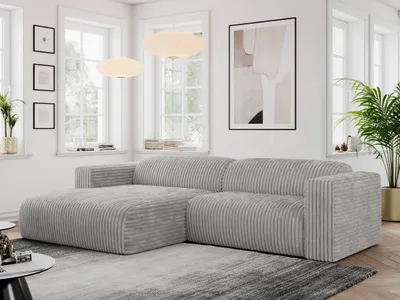 A modern living room with a light gray cord sofa, large windows, and artwork on the wall.