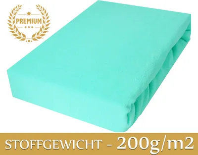 A folded turquoise fitted sheet is shown on a white background. A 'PREMIUM' badge is in the top left corner, and text indicating fabric weight is at the bottom.