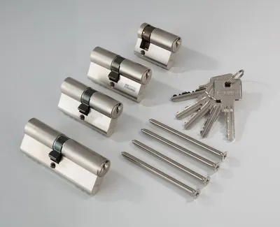 A set of four cylinder locks and five keys are laid out on a light gray surface.