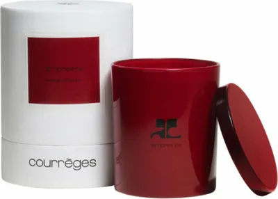 A red scented candle with its lid and packaging.