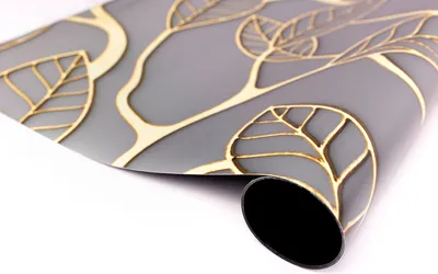 A rolled-up piece of wallpaper with a gray background and a gold leaf pattern.