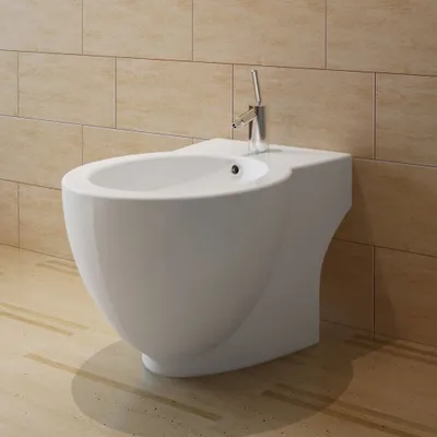 A white ceramic bidet with a chrome faucet is shown against a tiled wall and wooden floor.