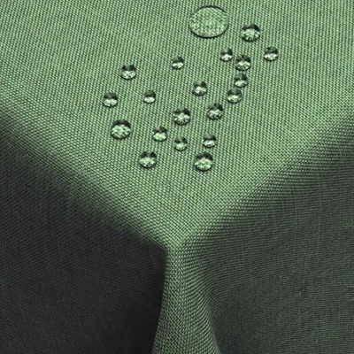 A close-up view of a dark green tablecloth with water droplets on it, showcasing its water-repellent feature.