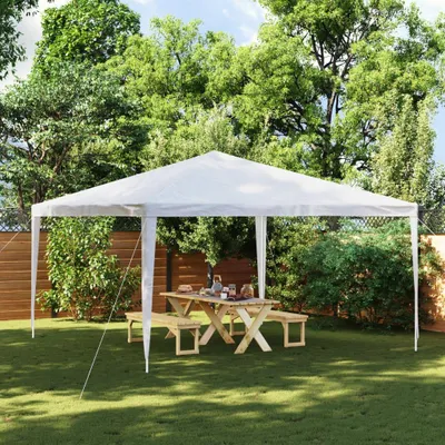 A white party tent set up in a backyard with a wooden picnic table and benches underneath.