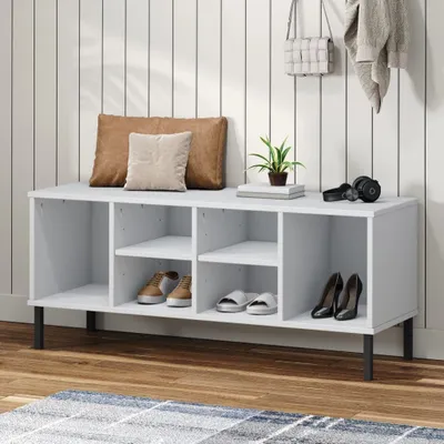 A white shoe storage bench with multiple compartments, holding shoes and decorative items, placed against a vertical white paneled wall.