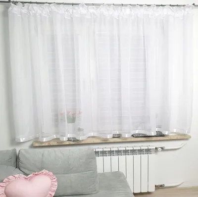 A white sheer curtain hangs over a window, with a radiator and part of a sofa visible below.