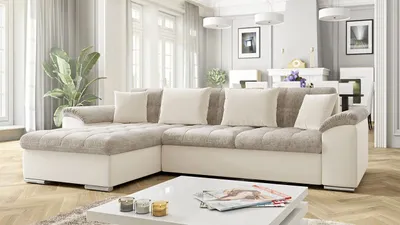 A sectional sofa is shown in a well-lit living room with large windows and decorative elements in the background.