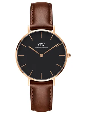 A close-up studio shot of a Daniel Wellington watch with a black face and a brown leather strap.