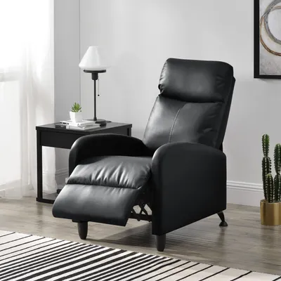 A black leather recliner chair is shown in a room with a side table and a lamp.