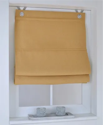 A yellow Roman blind is shown hanging in a window frame, with two decorative candle holders on the windowsill below.