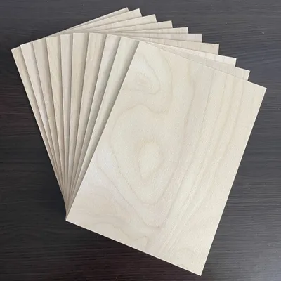 A stack of thin wooden sheets fanned out on a dark surface.